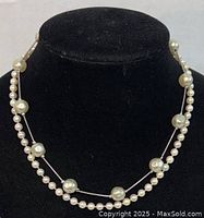 Double strand pearl necklace displayed on black velvet bust, showing strands with varying pearl sizes and white gold/silver clasp