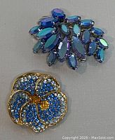 Both vintage blue rhinestone brooches displayed showing floral and cluster design