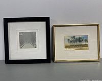 Two vintage framed watercolors by A. Soffer side by side on gray surface against white wall.