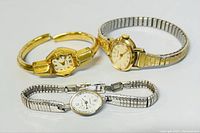 Three vintage women's wristwatches including a gold expression bangle style, silver-tone expansion bracelet, and a two-tone expansion bracelet watch.