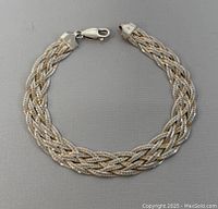 Full view of the silver braided woven bracelet laid flat showing clasp and overall design.