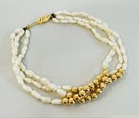 Full view of the 7 inch freshwater pearl bracelet with 14K yellow gold beads and clasp, laid flat on a light surface.