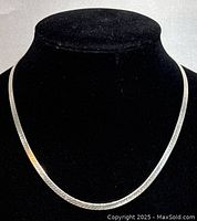 Full view of the necklace displayed on a black bust showing length and shine.