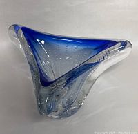 Triangular art glass bowl with blue rim and embedded controlled bubbles shown at an angle, highlighting the thickness and clarity of the glass.