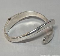 Silver modernist cuff bangle with open ends and hallmark stamps visible inside the band