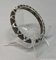 Bangle displayed on clear stand showing silver and black inlay pattern design.