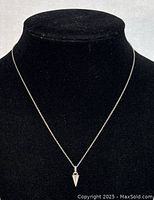 Front view of the necklace on a black display bust showing the cone pendant and chain length.