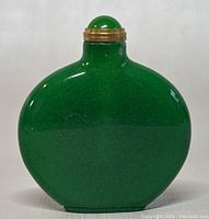 Front view of spinach green jade snuff or perfume bottle showing smooth and glossy surface with minor speckling.