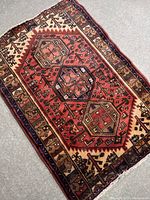 Angled view showing the full rug with a central medallion and patterned border, highlighting condition and colors.