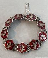 Top view of vintage Siam sterling silver link bracelet with red enamel and Siamese motifs on each link.