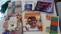Photo showing six knitting and textile-related books arranged on a light surface, highlighting book covers and titles for identification.