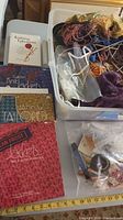 Photo showing knitting and tailoring books alongside yarn and knitting tools in a box