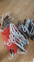 Variety of hangers including white plastic multi-hook hangers, black plastic hangers, some wooden hangers bundled with a red bag.