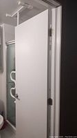 White door with metal security pole positioned inside the door frame for security or support.