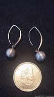 Pair of sterling silver 925 stamped dangle earrings with a spherical bead shown with a coin for size reference.