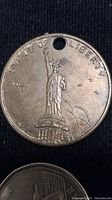 Close-up photo of brass token with raised image of Statue of Liberty and surrounding text 'STATUE OF LIBERTY'