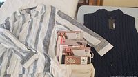 Striped blouse laid out on bed with navy blue sleeveless sweater and packages of pantyhose arranged on top.