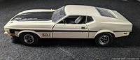 Side profile of 1971 Mustang Mach 1 die cast model in white with black hood and Mach 1 decal on door.
