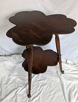 Two-tier quarter-sawn oak cloverleaf parlor table with fluted turned legs and brass-clad claw and glass ball feet.
