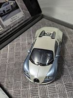 Front three-quarter view of white and light blue Bugatti Veyron model inside display case