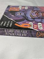 Close-up of box corner showing '6 cards per pack, 18 packs per box' and artwork of a gargoyle character.