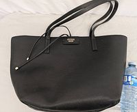 Front view of Guess black tote bag with shoulder straps and logo plate