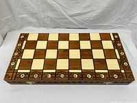 Closed folding chessboard showing the light and dark wooden squares with engraved letter and number coordinates on the edges