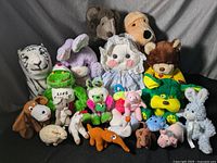 Full group of older stuffed animal toys arranged on a gray backdrop