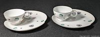 Two sets showing cups on 8-inch appetizer plates with MCM atomic designs in pastel colors and silver trim