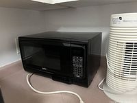 Black Salton microwave oven closed, showing the keypad panel and power cord.