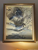 Framed 3D artwork showing two blue jays in winter by a stream with a gold-tone frame.