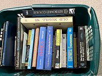 Photo showing a plastic bin containing various educational and textbook style books including math, physics, engineering, and piano instruction books.