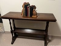 Full view of antique wooden console table with books and wooden bookends on top