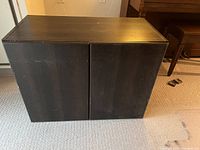 Dark brown wooden cabinet with closed removable doors, showing some surface wear.