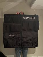 Front view of black hanging organizer with Sylvansport branding, showing multiple different-sized pockets including mesh and fabric pouches.
