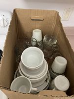 Box contains various cups, mugs including Simpsons Sedgewood patterned cups, stacked small plates and bowls, clear glasses