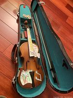 Violin with stickers inside the open hard shell case next to violin bow