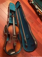 Violin, bow and open case interior showing teal plush lining