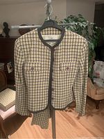 Full view of the tweed jacket on hanger showing front design and pattern