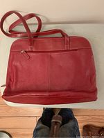 Front view of red leather Buxton laptop satchel purse showing front zippered pocket and carrying straps