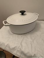 White enameled cast iron roasting pot with lid, showing pot and handles
