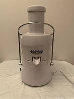 Front view of white Jack LaLanne Power Juicer with metal locking arm and power cord.