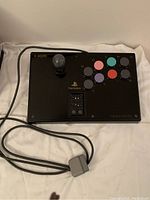 Full view of the Hori Fighting Stick PS for PlayStation showing joystick, buttons, logos, and cable.