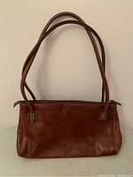 Full front view of brown leather purse showing classic rectangular shape, double shoulder straps, and clean leather surface.