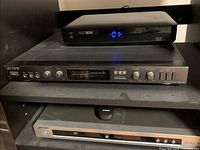 Sony karaoke mixer on middle shelf with Cisco NextBox above and Samsung DVD player below on the bottom shelf.