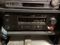 Yamaha HTR-5950 AV receiver on shelf with connected cables and remote control resting beside it.