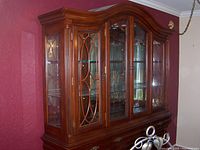Full view of the formal dining room china cabinet showing the wood construction, curved top, and glass display doors.