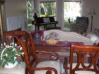 Photo showing two reddish-brown wooden formal dining chairs with carved details and cushioned seats in a living room environment.