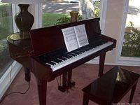 Photo of a dark wood upright piano with three pedals and sheet music on the music stand.