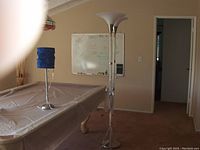 Photo of two standing lamps near a pool table, one with a blue fabric shade and one with a white upward-facing shade.